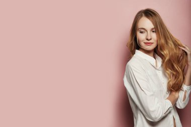 Pembe bir arka plan üzerinde beyaz bir gömlek giymiş beyaz güzel bir kadın uzun saçlı portresi
