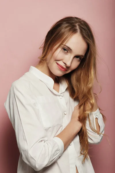ピンクの背景に白いシャツを着て長い髪のきれいな白人女性の肖像画 — ストック写真
