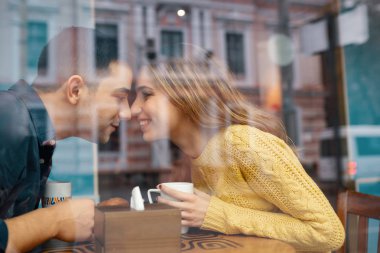Genç çekici çift tarihte kahve dükkan, ilk öpücük, birbirleri ile harcanan vaktinizi. Şehir binaları yansıtan camdan ateş.