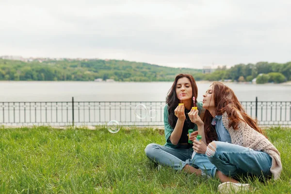 Two Sisters Having Fun While Making Bubbles Sitting Grass Lake — Stock Photo, Image