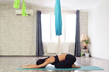 Çocuk poz bir yoga mat üzerinde oturan bir genç kadının tam uzunlukta