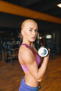 Eğitim silah spor yaparken dumbbells ile egzersiz yaparak beyaz bir genç kadın. Güç ve motivasyon kavramı. Yan görünüm 