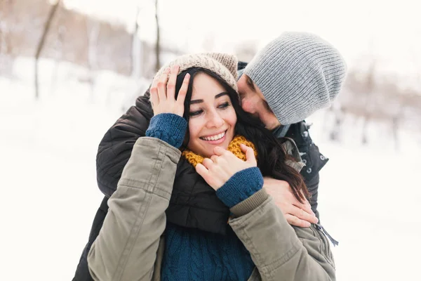 愉快的年轻夫妇享受寒假微笑和拥抱在一个模糊的冬天风景背景 — 图库照片