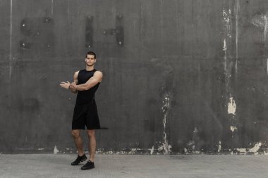 Isınma, arka planda gri bir kentsel Duvar ile eğitim için hazırlık güçlü kas, sportif adam. Genç sporcu elleri ve triceps germe. Egzersiz ve egzersiz kavramı