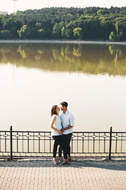Hamile eşi güzel manzaraya sarılma beyaz delikanlı. Aile kavramı. Gülümseyen anne ve mutlu baba. Hamile kadın sevilen duygu. Güzel insanlar.