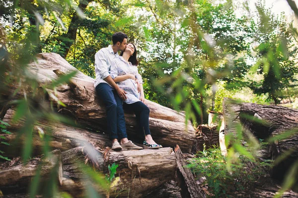 Красивая Беременная Пара Отдыхает Лесу Сидя Целуясь Стебле Дерева Зелеными — стоковое фото