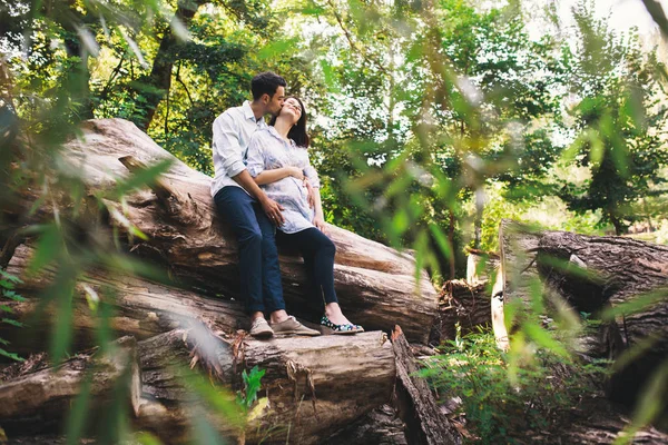 Vackra Gravida Par Avkopplande Utanför Skogen Medan Sitter Och Kyssas — Stockfoto