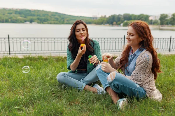 Two Sisters Having Fun While Making Bubbles Sitting Grass Lake — Stock Photo, Image