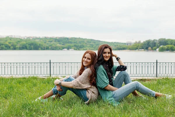 Smiling Brunette Reddish Girls Sitting Back Back Grass Looking Camera — Stock Photo, Image