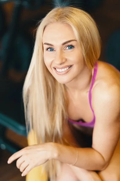 Retrato de uma jovem loira saudável com o cabelo longo sorrindo enquanto relaxa no ginásio — Fotografia de Stock