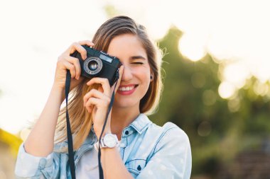 Güzel kız güneşli bir günde bir vintage kamera ile fotoğraf çekmek