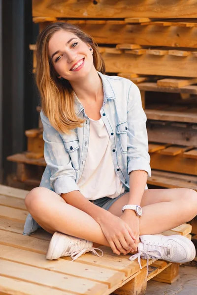 Pretty glimlachend meisje, het dragen van jeans, shorts en shirt poseren op hout achtergrond — Stockfoto