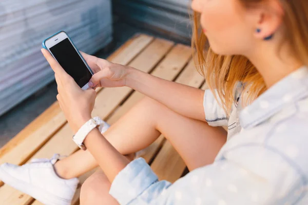 Mulher bonita segurando o telefone nas mãos enquanto toca na tela — Fotografia de Stock