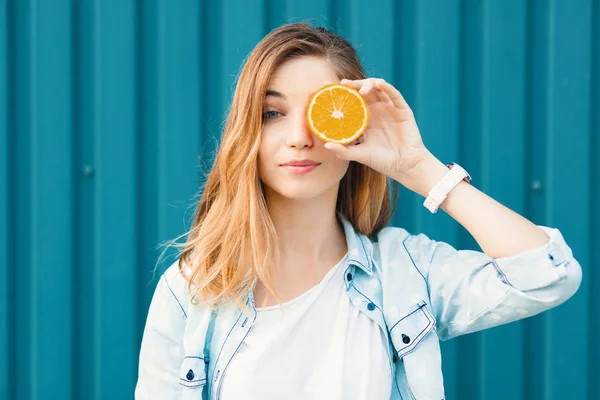 Despreocupado jovem menina bonita usando duas metades em laranjas em vez de óculos sobre os olhos — Fotografia de Stock