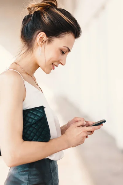 Вид сбоку портрет улыбающейся элегантной молодой женщины с помощью смартфона — стоковое фото