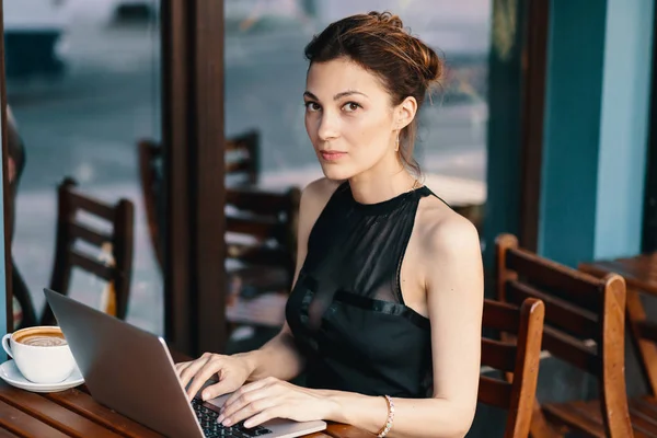 Raffinierte Geschäftsfrau mit Brille sitzt am Tisch im Café und arbeitet am Laptop — Stockfoto