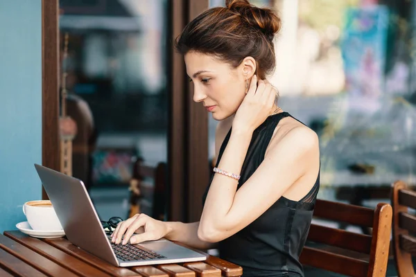 Mulher de negócios refinada em óculos, sentada à mesa no café trabalhando no laptop — Fotografia de Stock