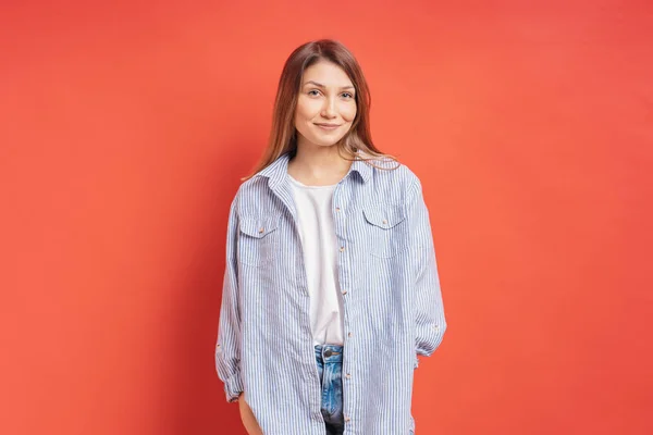 Jolie modèle féminin posant avec une expression de visage souriante sur fond rouge — Photo