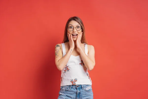 Emoções de pessoas - retrato de menina positiva surpreso sobre fundo vermelho — Fotografia de Stock