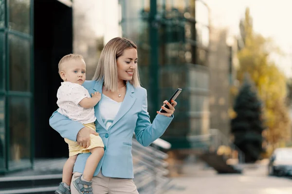 Retrato de uma mulher de negócios bem sucedida em terno azul com bebê — Fotografia de Stock
