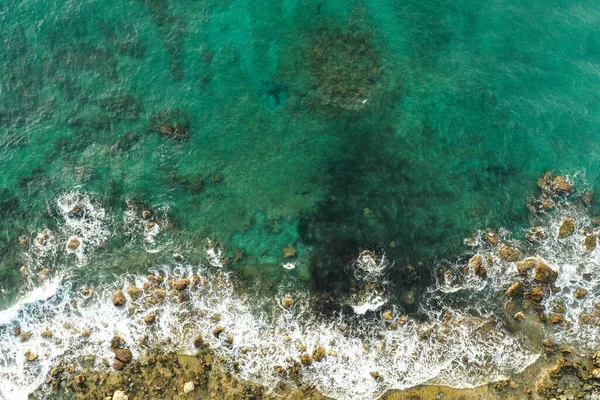 Aerial view of sea meeting rocky shore