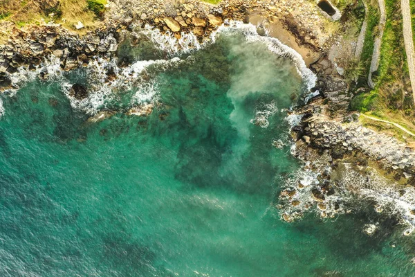 Aerial view of sea meeting rocky shore