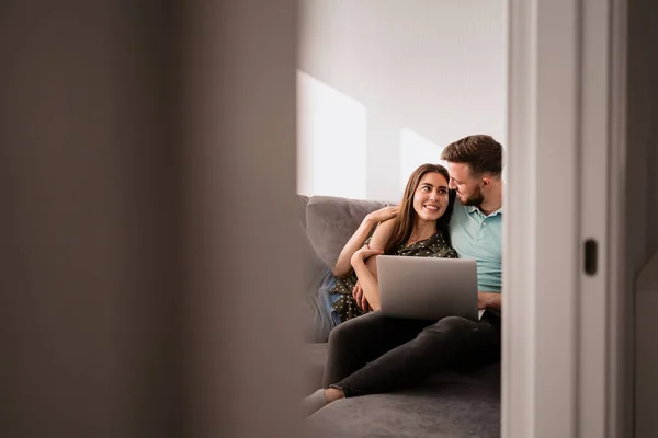 Hombre y mujer sentados en un sofá con un portátil — Foto de Stock