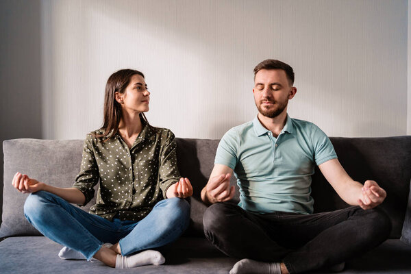 Man and woman sitting on sofa in lotus pose