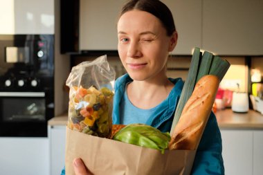Evde alışveriş torbalarıyla sağlıklı genç bir kadın.
