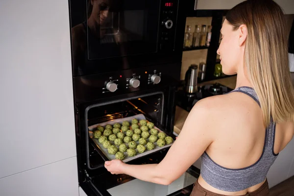 Heerlijk fit vrouw zet in de oven een dienblad met falafel — Stockfoto