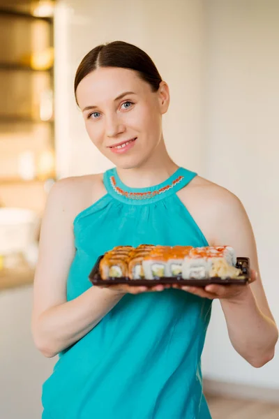 Mulher encantadora segurando um prato com rolos de sushi em suas mãos — Fotografia de Stock