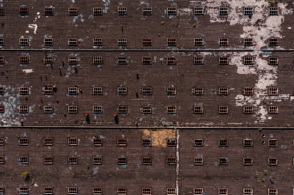 Eine Luftaufnahme von einem großen Fabrikdach, aufgenommen mit einer Drohne. Abstraktes Streifenmuster von Fenstern für Hintergründe — Stockbild Draufsicht auf die Dachstruktur mit Fenstern — Stockfoto
