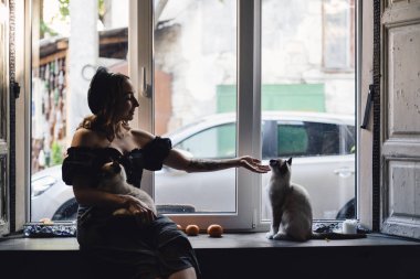 Siyam kedileriyle oynayan güzel kadın