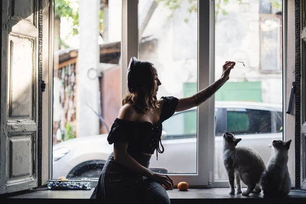 Hübsche Frau spielt mit siamesischen Katzen — Stockfoto