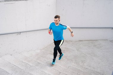 Genç adam merdivenlerde antrenman yapıyor.