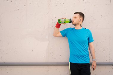 Egzersizler sırasında su içen beyaz bir adam.