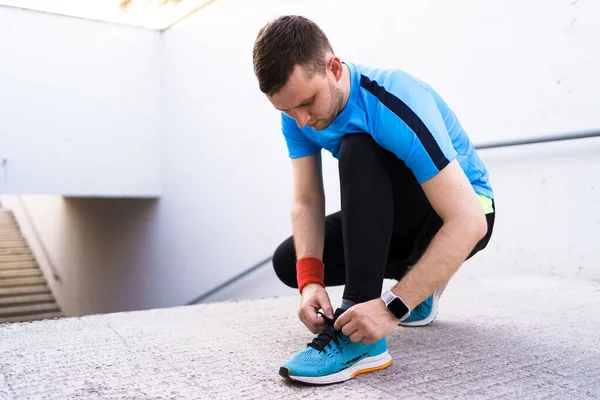 Man tying his sport shoes on concrete background