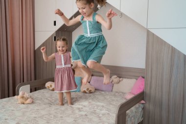 Odadaki yatakta zıplayan tatlı kızlar.