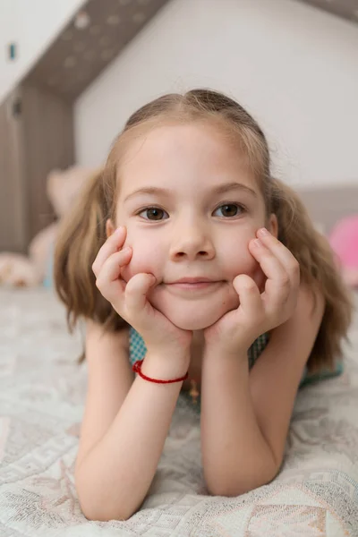 Nettes Mädchen macht lustige Gesichter auf dem Bett — Stockfoto