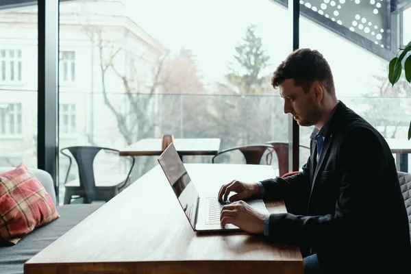 Бизнесмен, сидя за деревянным столом, пользуется ноутбуком — стоковое фото