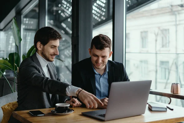 Zwei Geschäftsleute zeigen beim Gespräch auf Laptop-Bildschirm — Stockfoto