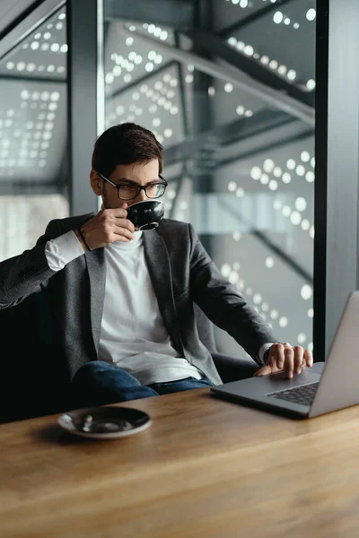 Başarılı bir iş adamı kahve içerken dizüstü bilgisayarda çalışıyor. — Stok fotoğraf