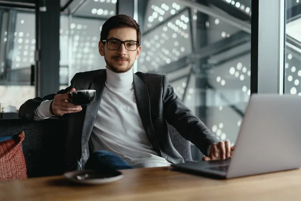 Erfolgreicher Geschäftsmann arbeitet beim Kaffeetrinken am Laptop — Stockfoto
