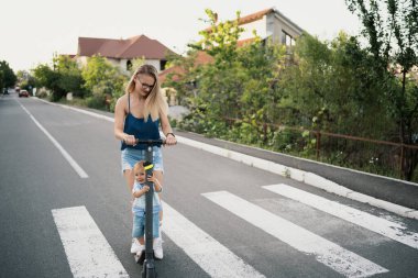 Anne ve oğlu elektrikli scooter kullanıyor.