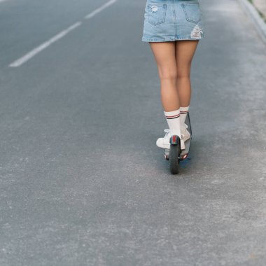 Milenyum kadını sokakta elektrikli scooter kullanıyor.