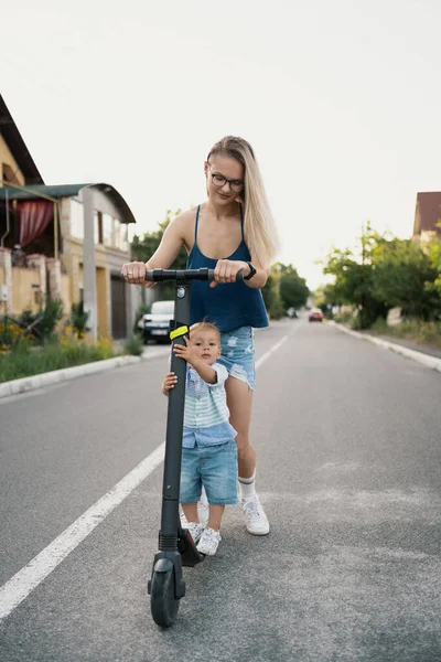 Мать и сын едут на электрическом скутере — стоковое фото