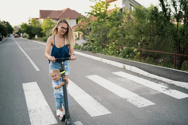 Мать и сын едут на электрическом скутере — стоковое фото