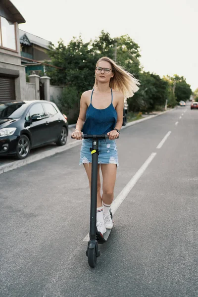Millennial donna cavalcando uno scooter elettrico in strada — Foto Stock