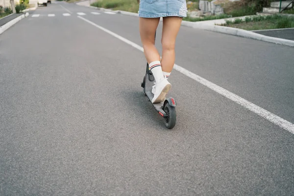 Millennial mulher montando uma scooter elétrica na rua — Fotografia de Stock