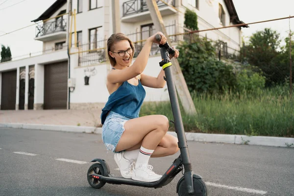 Millennial kvinna rida en elektrisk skoter på gatan — Stockfoto